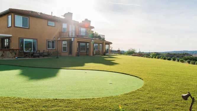 Backyard putting green with a home in the background